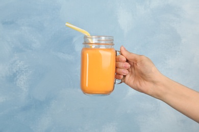 Woman holding mason jar with delicious smoothie on color background