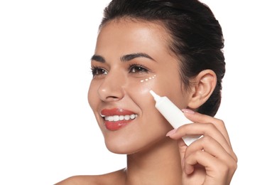 Woman applying cream under eyes on white background. Skin care