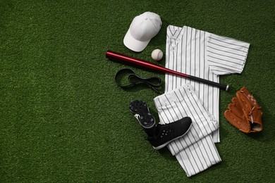 Baseball uniform and other sports equipment on artificial grass, flat lay. Space for text