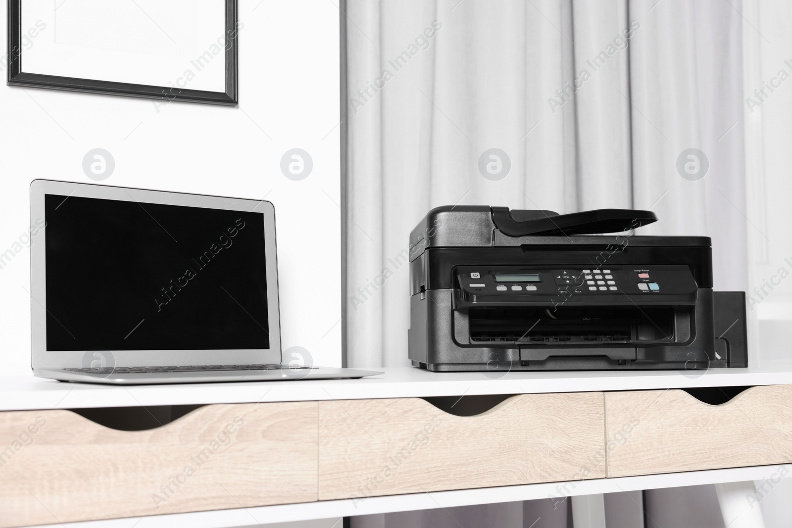 Photo of Modern printer with paper near laptop on white desk at home