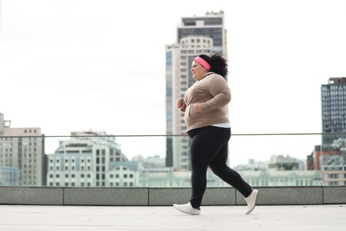 Beautiful overweight woman running outdoors. Fitness lifestyle