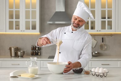 Professional chef making dough at white marble table in kitchen