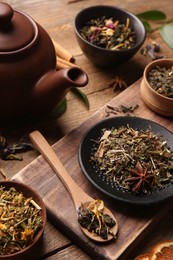 Photo of Different dry aromatic teas on wooden table