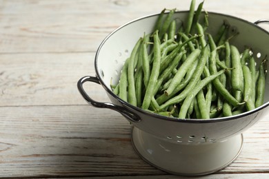 Photo of Fresh green beans in colander on white wooden table