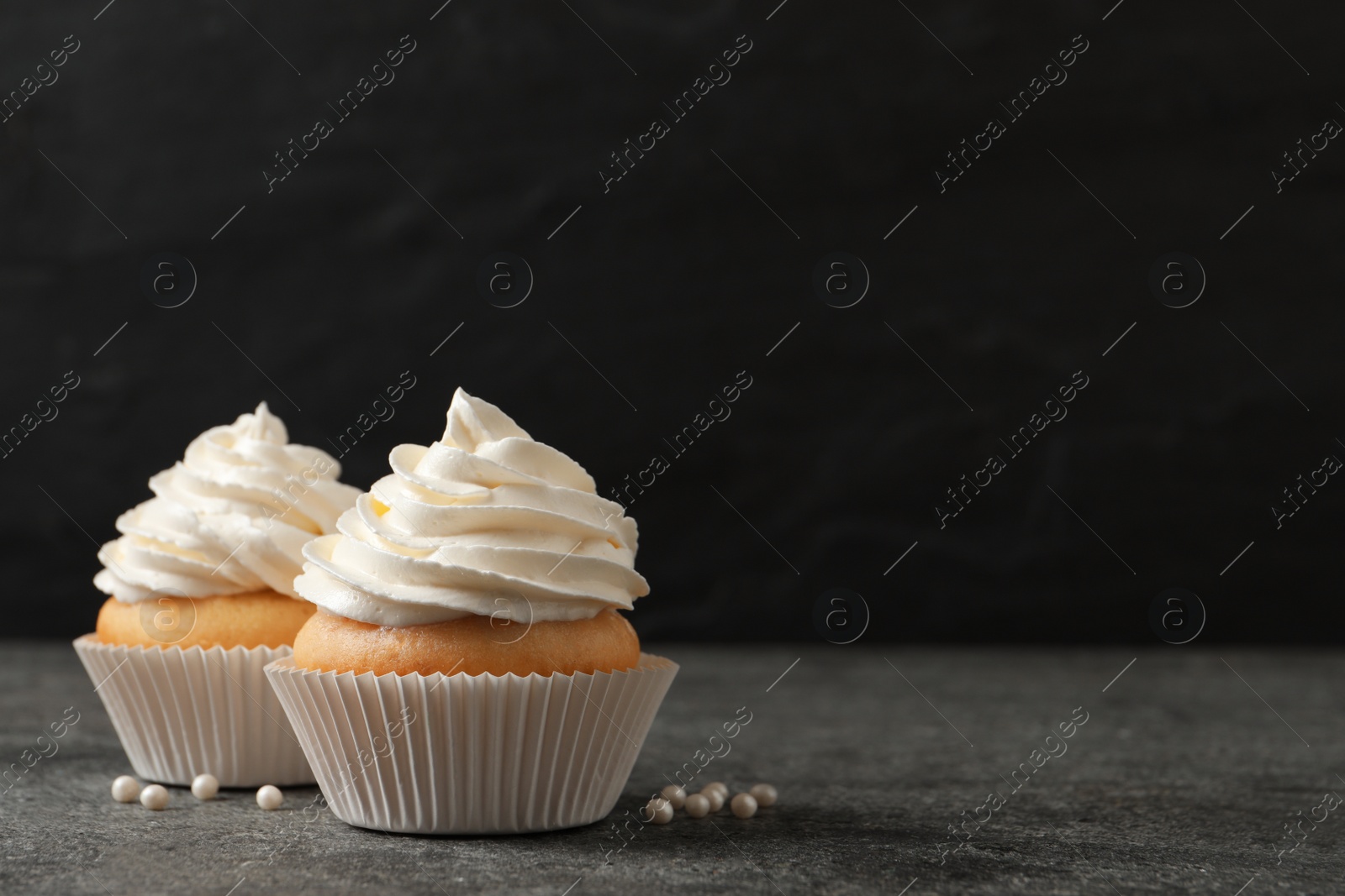 Photo of Delicious cupcakes with cream on grey table. Space for text