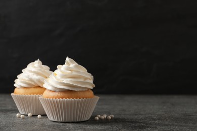 Delicious cupcakes with cream on grey table. Space for text