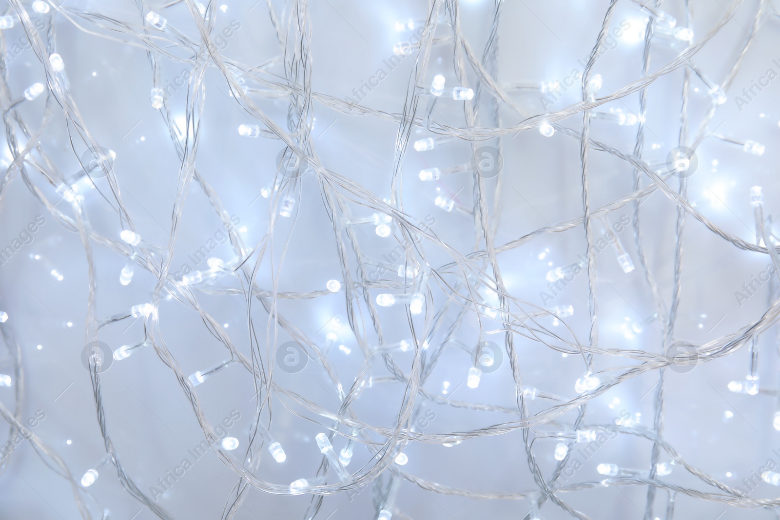 Photo of Glowing Christmas garland on light background, closeup