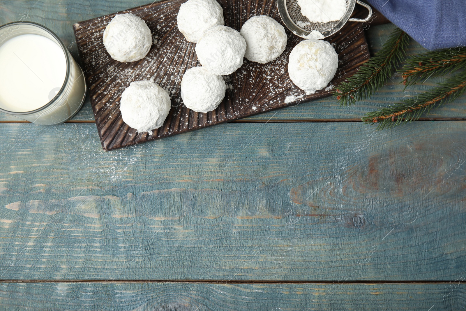 Photo of Flat lay composition with tasty Christmas snowball cookies on blue wooden table. Space for text
