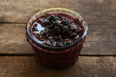 Photo of Bowl of sweet black mulberry jam on wooden table