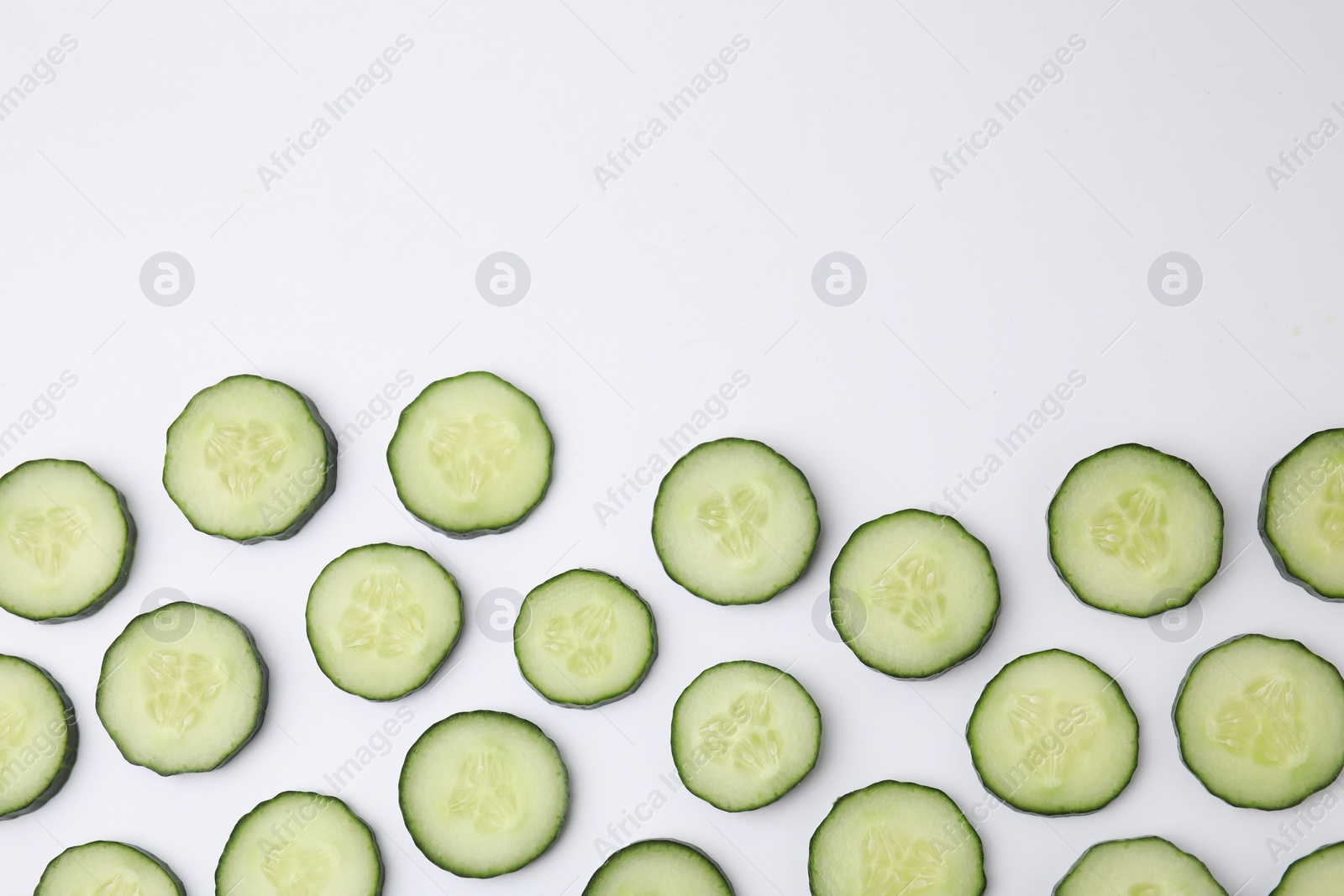 Photo of Fresh slices of cucumbers on white background, top view. Space for text