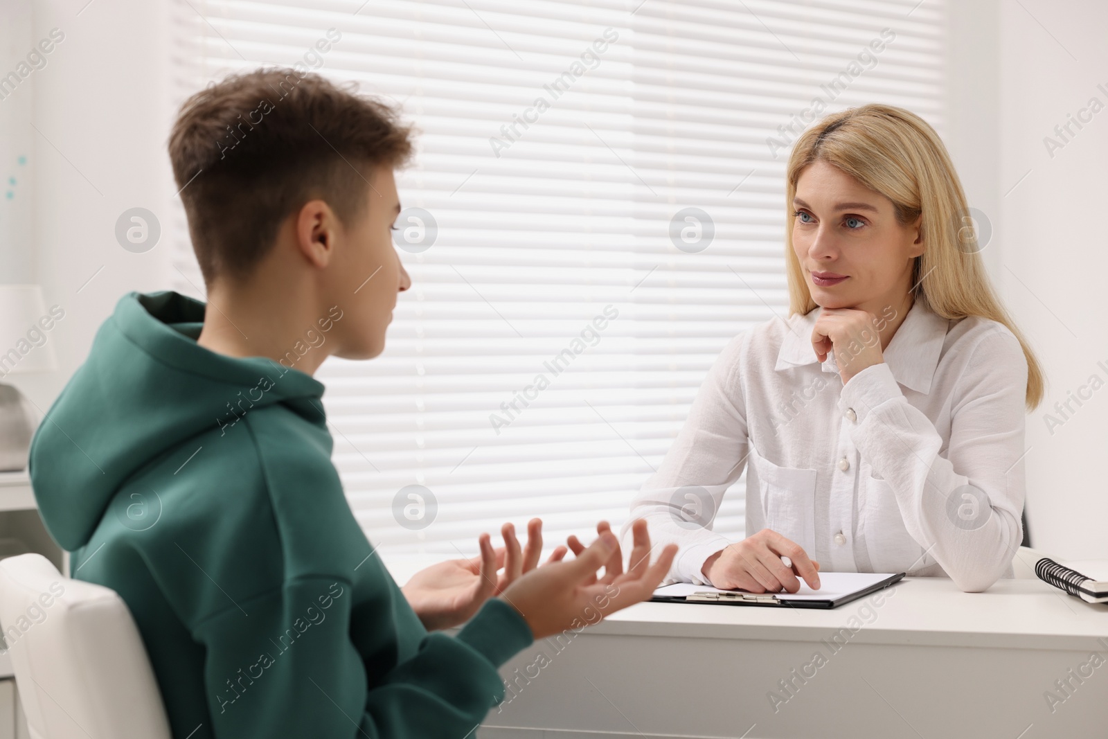 Photo of Psychologist working with teenage boy at table in office