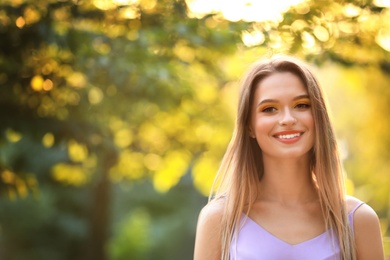 Beautiful young woman posing outdoors on sunny day