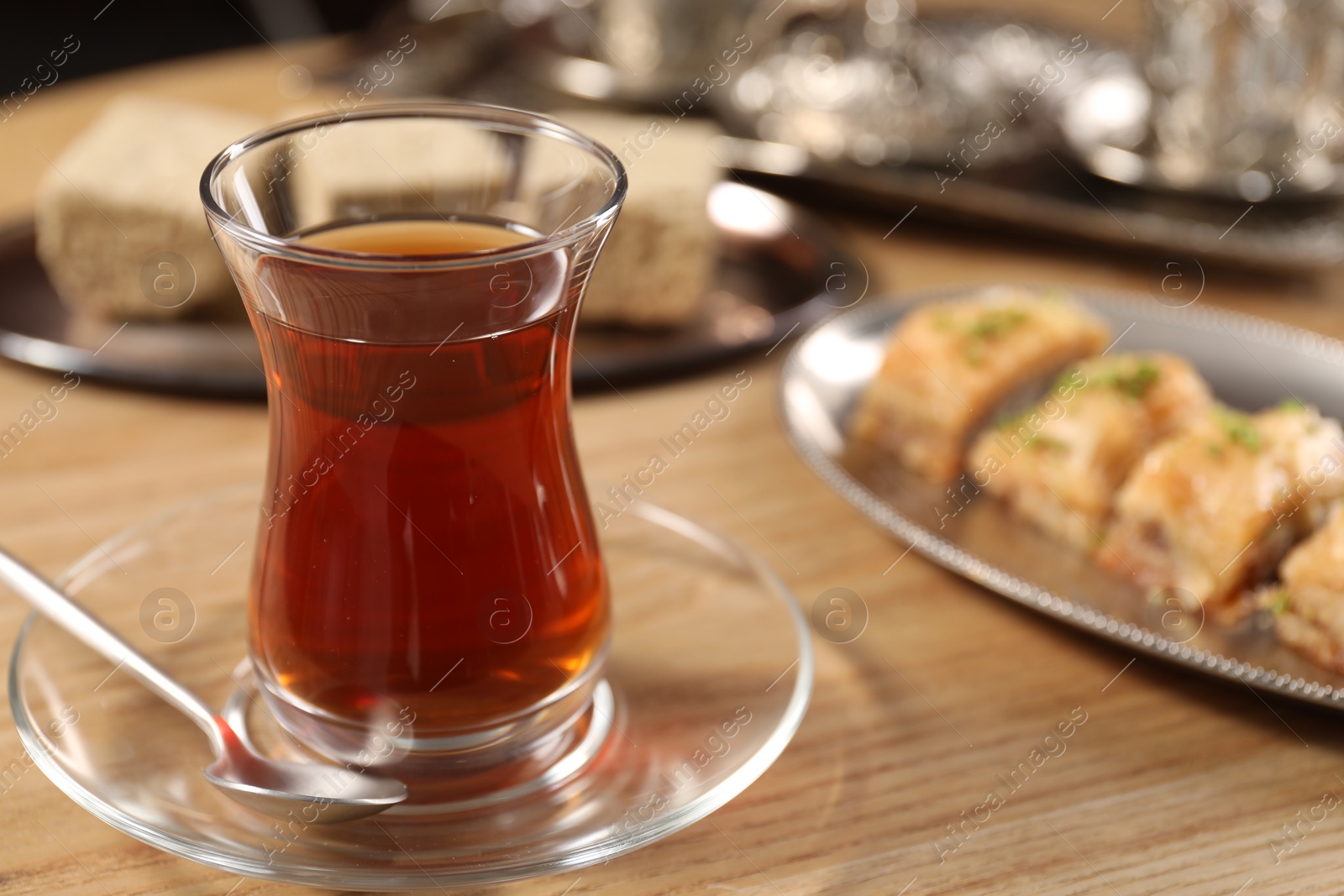 Photo of Traditional Turkish tea in glass on wooden table, closeup. Space for text