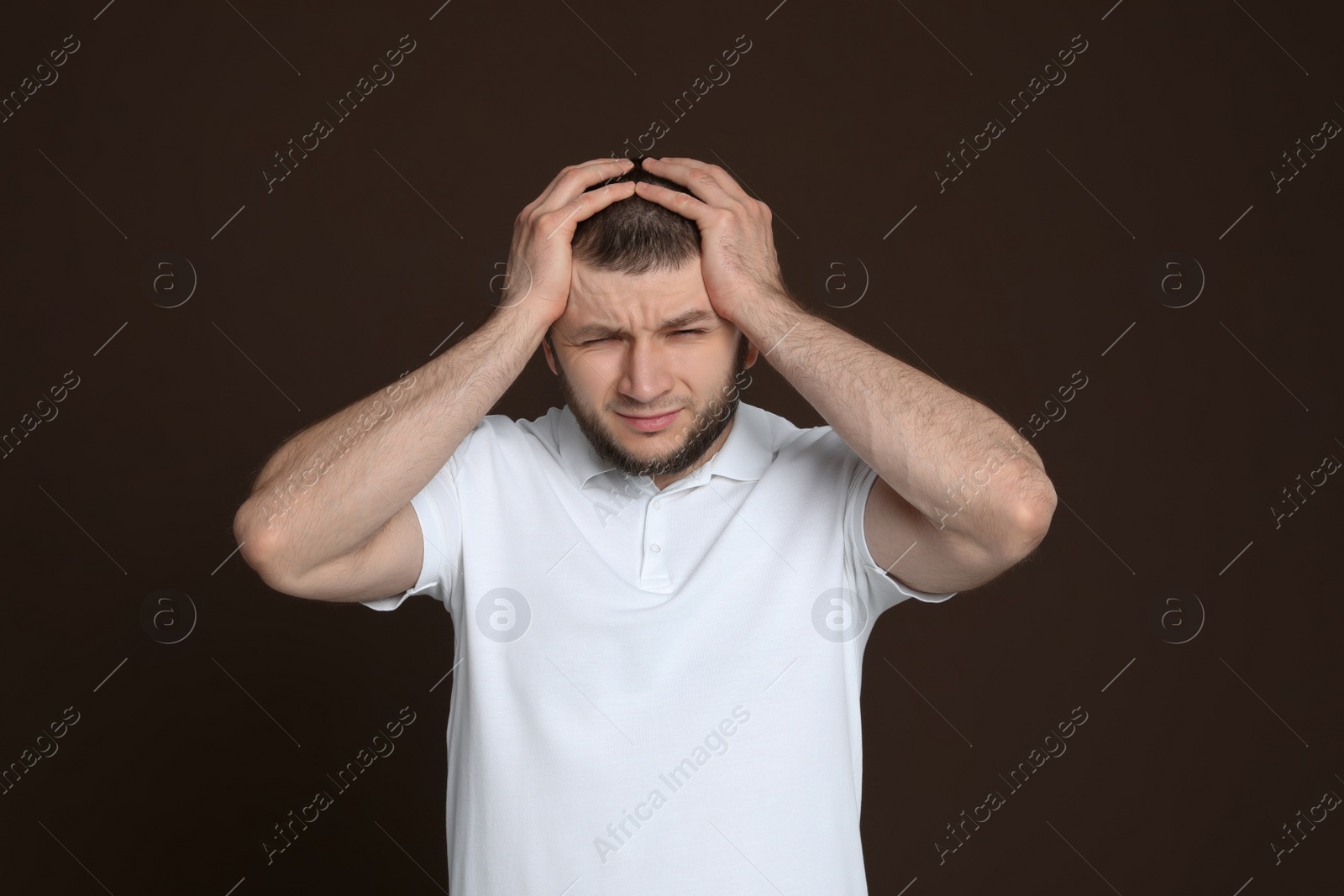 Photo of Man suffering from headache on dark brown background