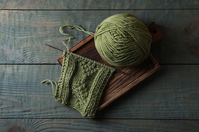 Soft yarn, knitting and metal needle on light blue wooden table, top view