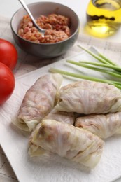 Photo of Uncooked stuffed cabbage rolls and ingredients on table, closeup
