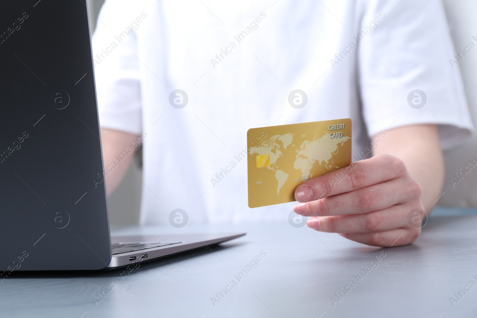 Photo of Online payment. Woman with laptop and credit card at white table, closeup