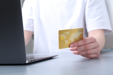 Online payment. Woman with laptop and credit card at white table, closeup