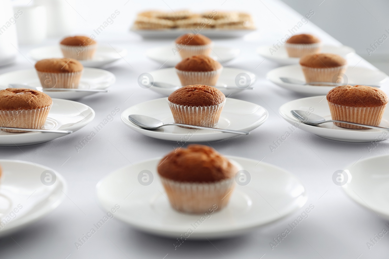 Photo of Many delicious muffins served on white table for coffee break