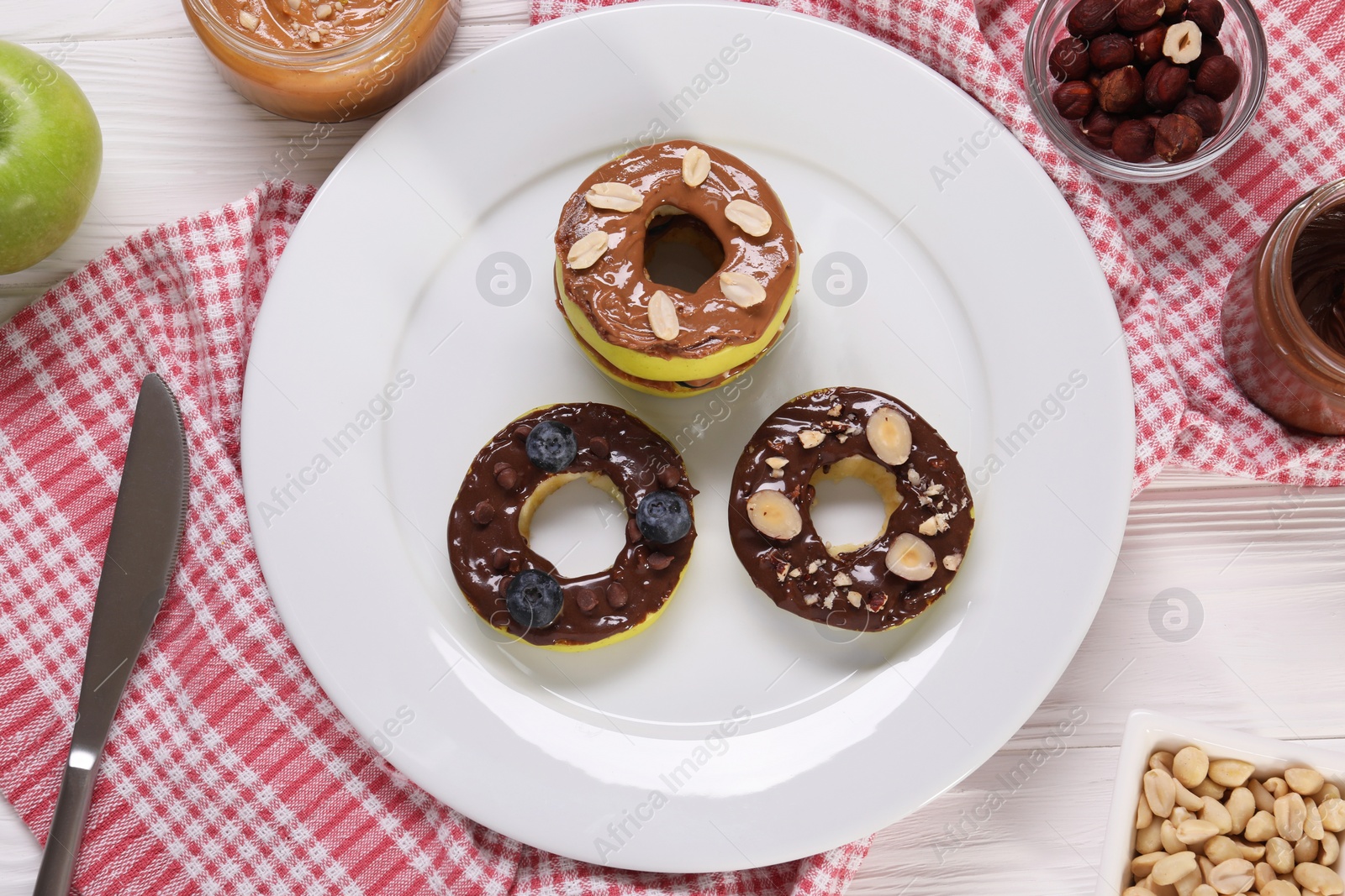 Photo of Fresh apples with nut butters, blueberries and nuts on white wooden table, flat lay