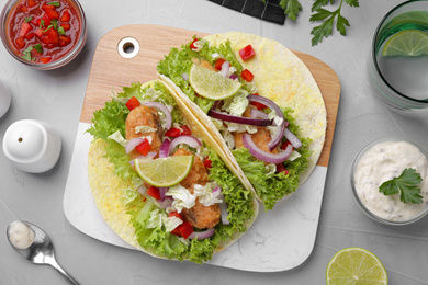 Photo of Delicious fish tacos served on light grey table, flat lay
