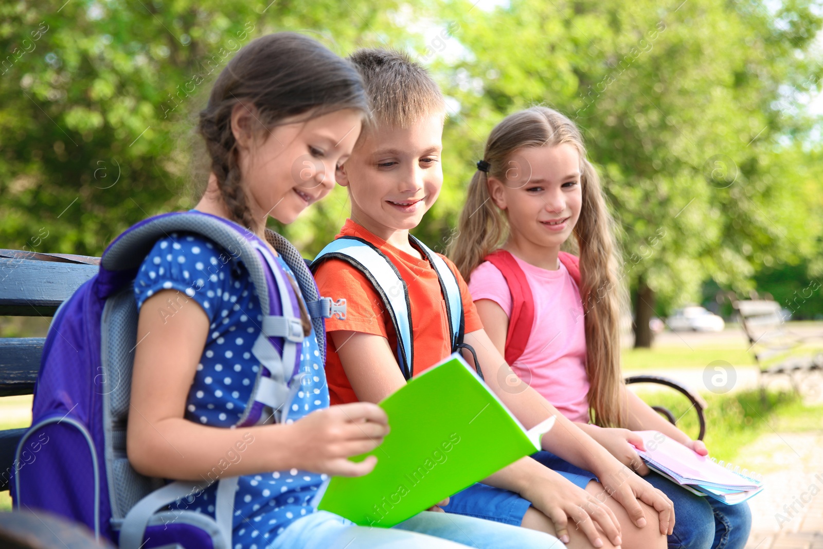 Photo of Cute little children with backpacks and notebooks outdoors. Elementary school