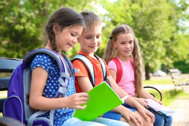 Cute little children with backpacks and notebooks outdoors. Elementary school