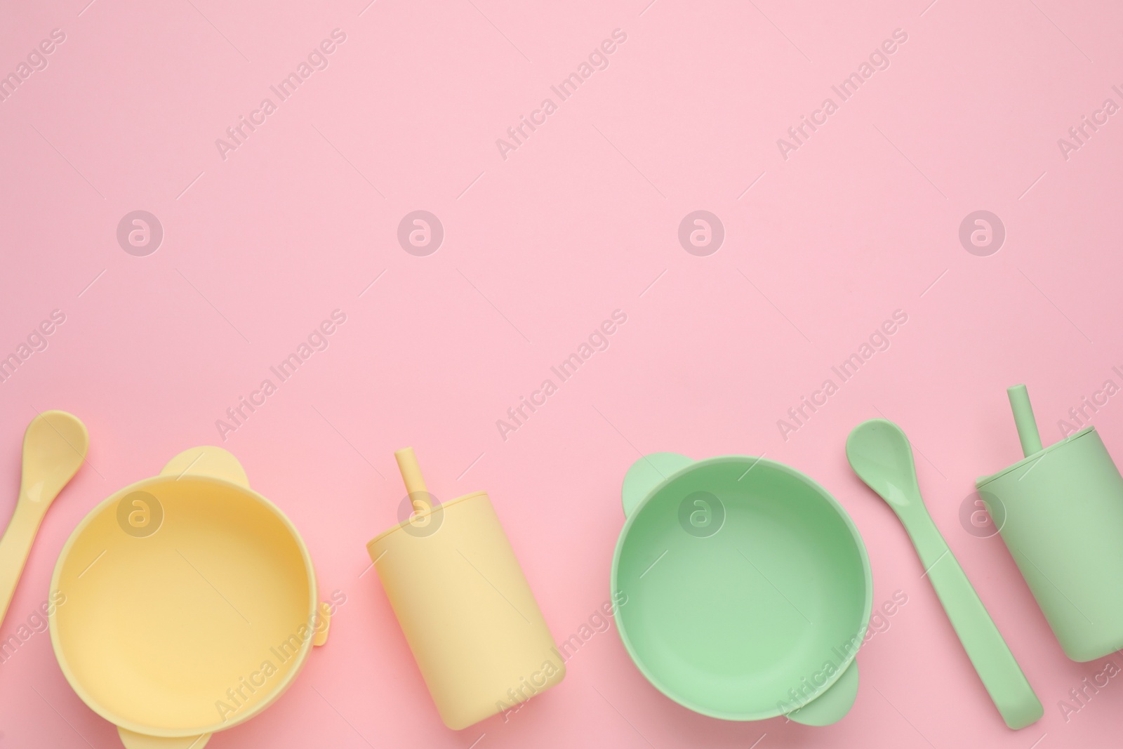 Photo of Set of plastic dishware on pink background, flat lay with space for text. Serving baby food