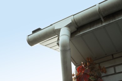 Photo of Rain gutter system with drainpipe on house outdoors, low angle view