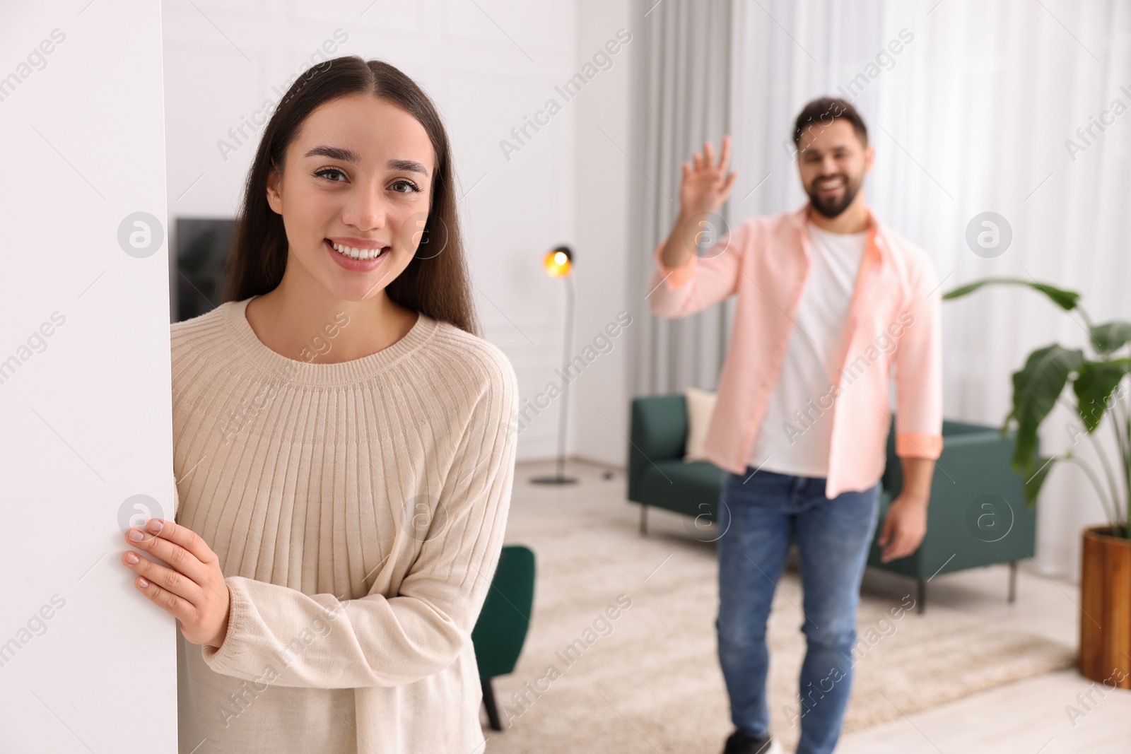 Photo of Happy couple welcoming at home. Invitation to come in room