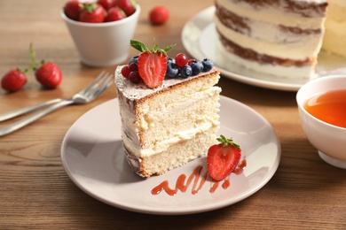 Photo of Piece of delicious homemade cake with fresh berries served on wooden table