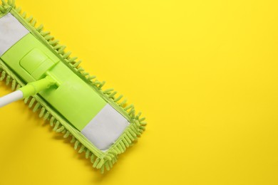 Photo of Mop with plastic handle on yellow background, top view. Space for text