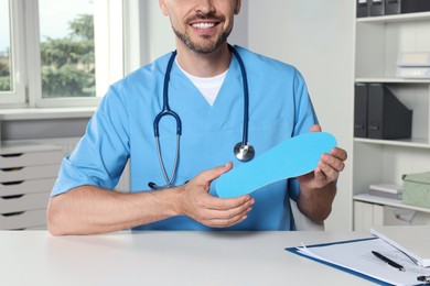 Male orthopedist showing insole in hospital, closeup