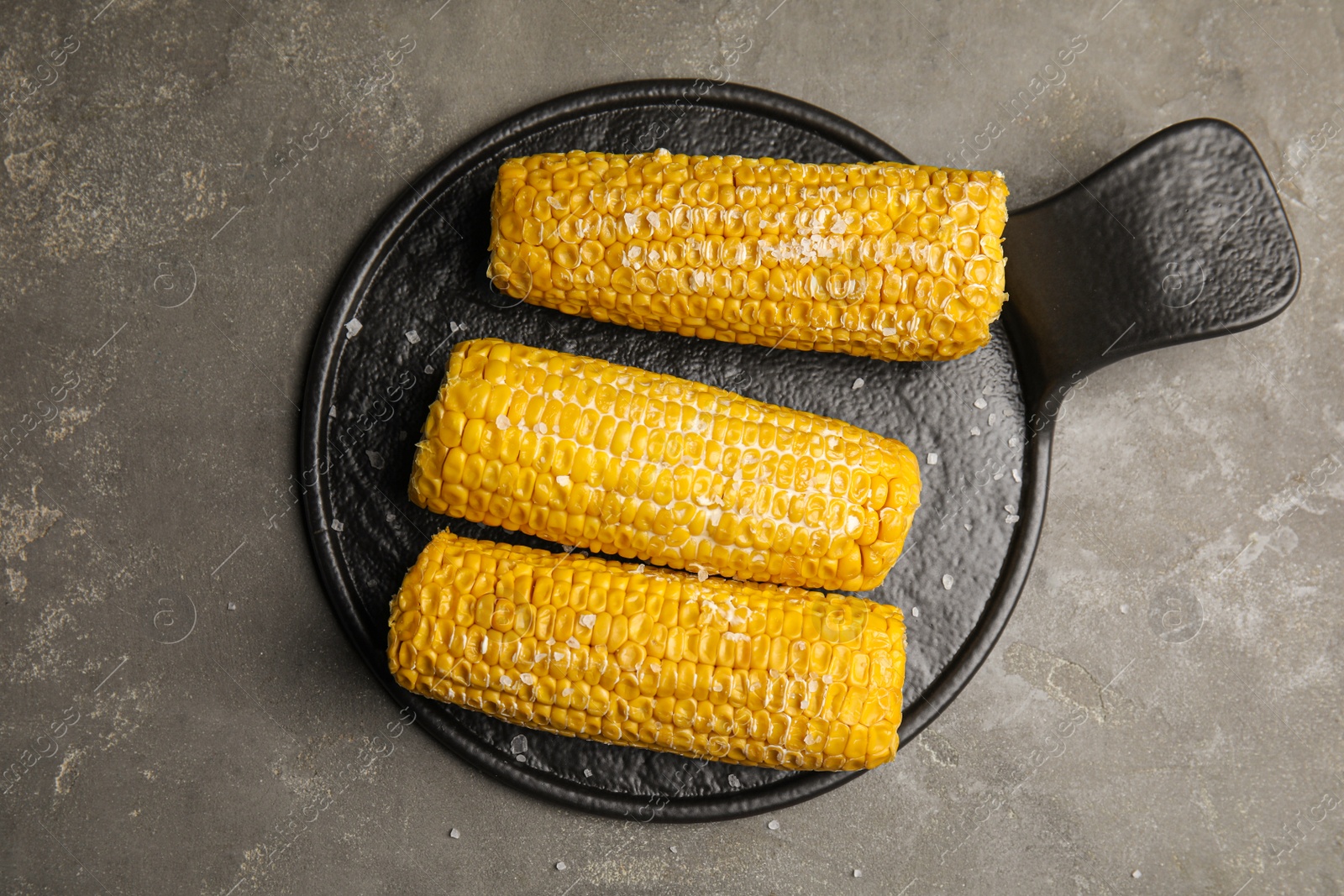 Photo of Delicious boiled corn with butter and salt on grey table, top view