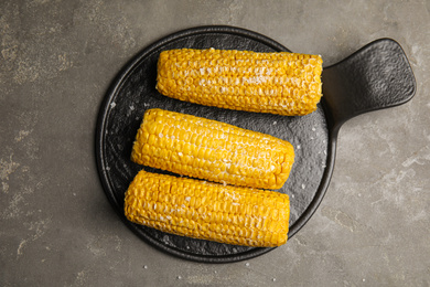 Delicious boiled corn with butter and salt on grey table, top view