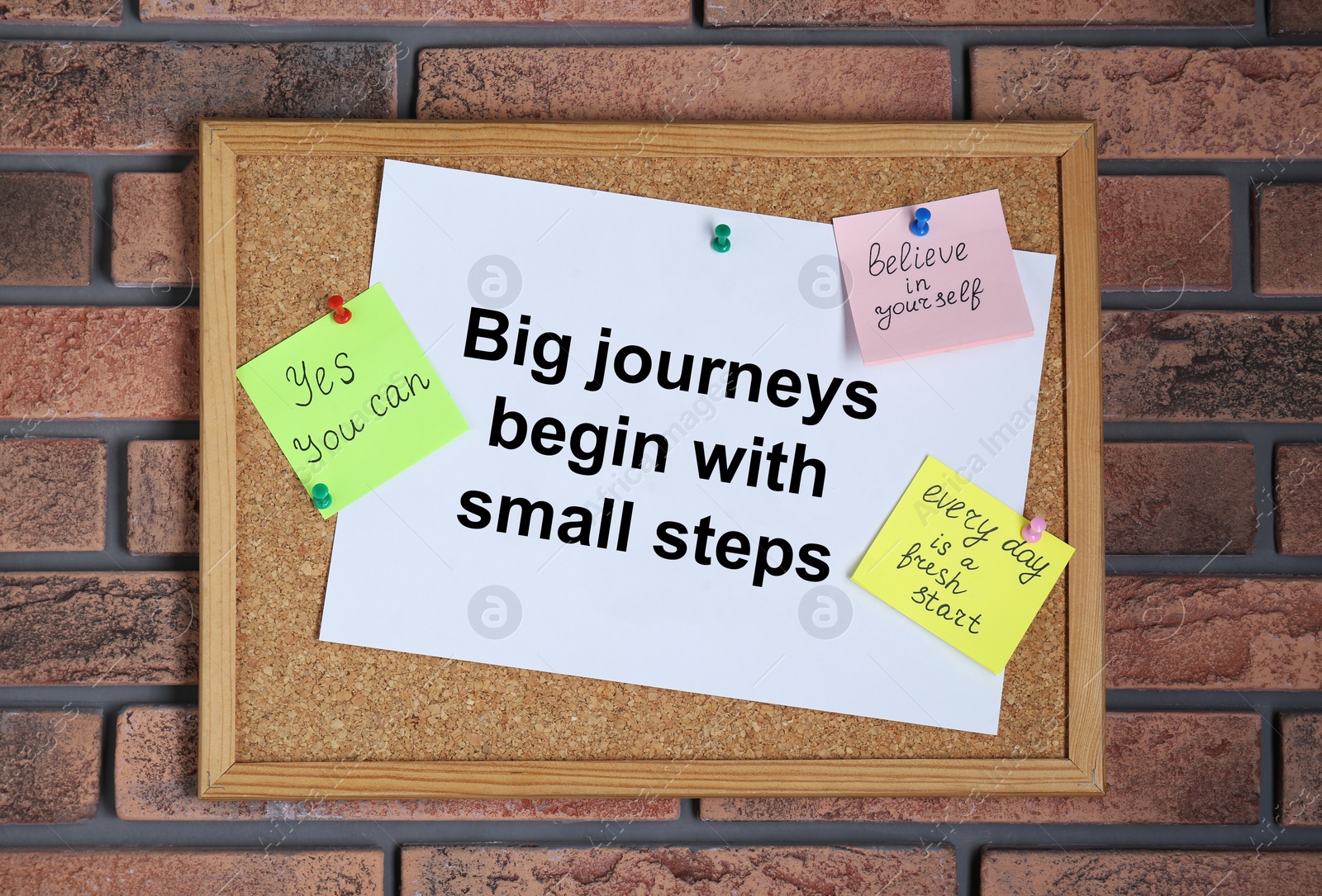 Photo of Corkboard with motivational quotes on brick wall