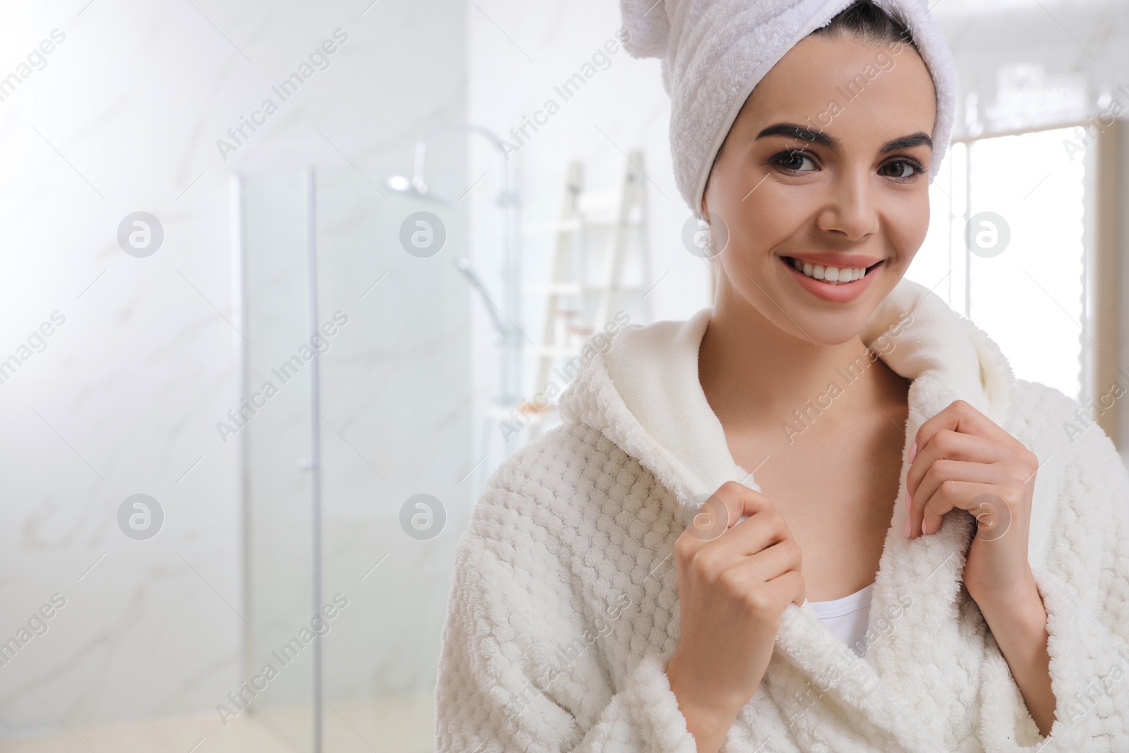 Photo of Happy young woman with towel on head in bathroom, space for text. Washing hair