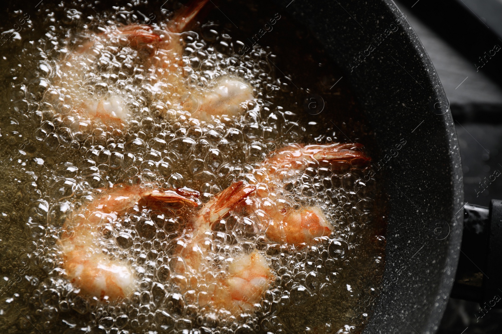 Photo of Cooking delicious shrimps in hot oil, closeup