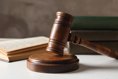 Wooden gavel and books on table against color background, closeup. Law concept