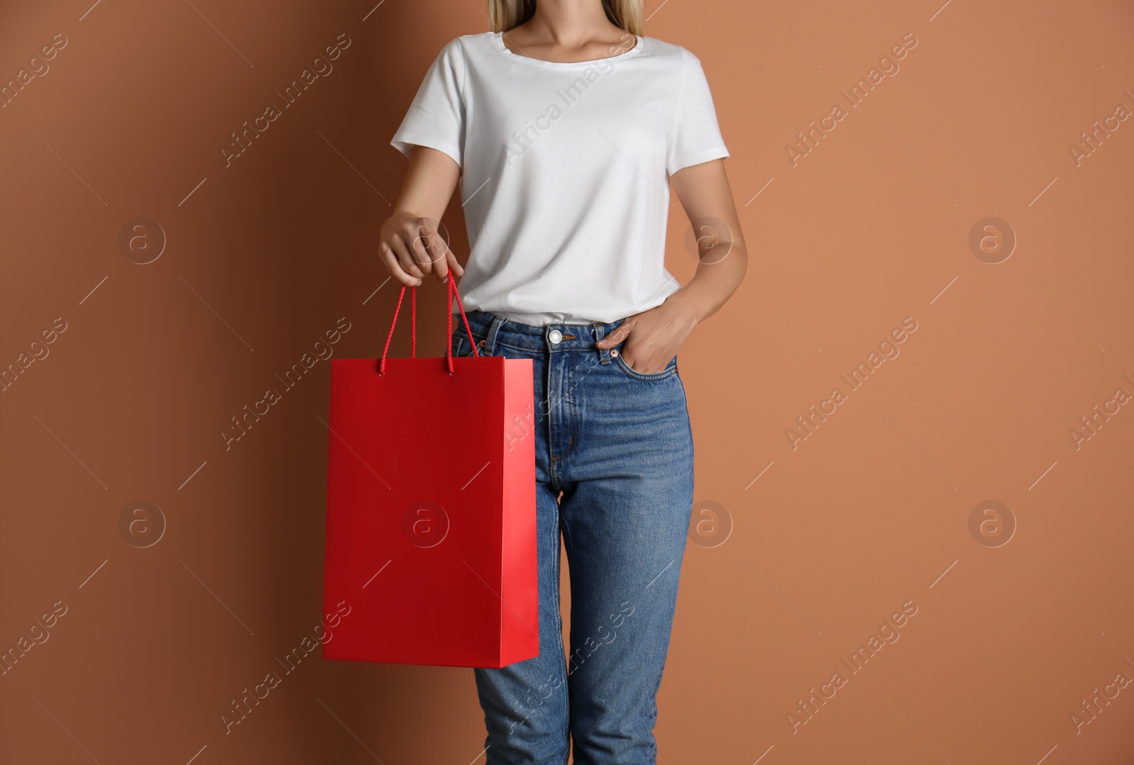 Photo of Woman with paper shopping bag on light brown background, closeup