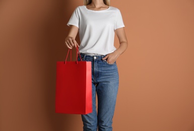 Photo of Woman with paper shopping bag on light brown background, closeup