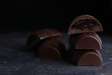 Tasty dark chocolate candies with jelly filling on black table, closeup. Space for text