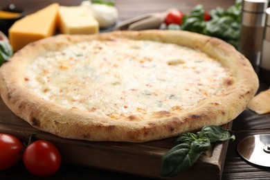 Photo of Delicious cheese pizza and ingredients on wooden table, closeup