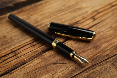 Beautiful fountain pen with ornate nib on wooden table, closeup