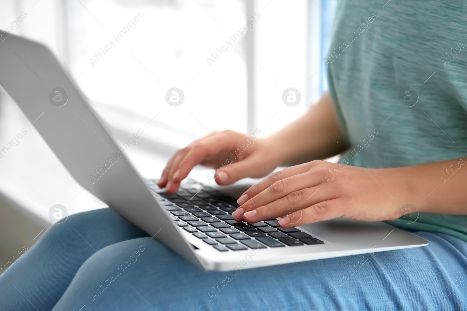 Photo of Young woman using laptop indoors, closeup