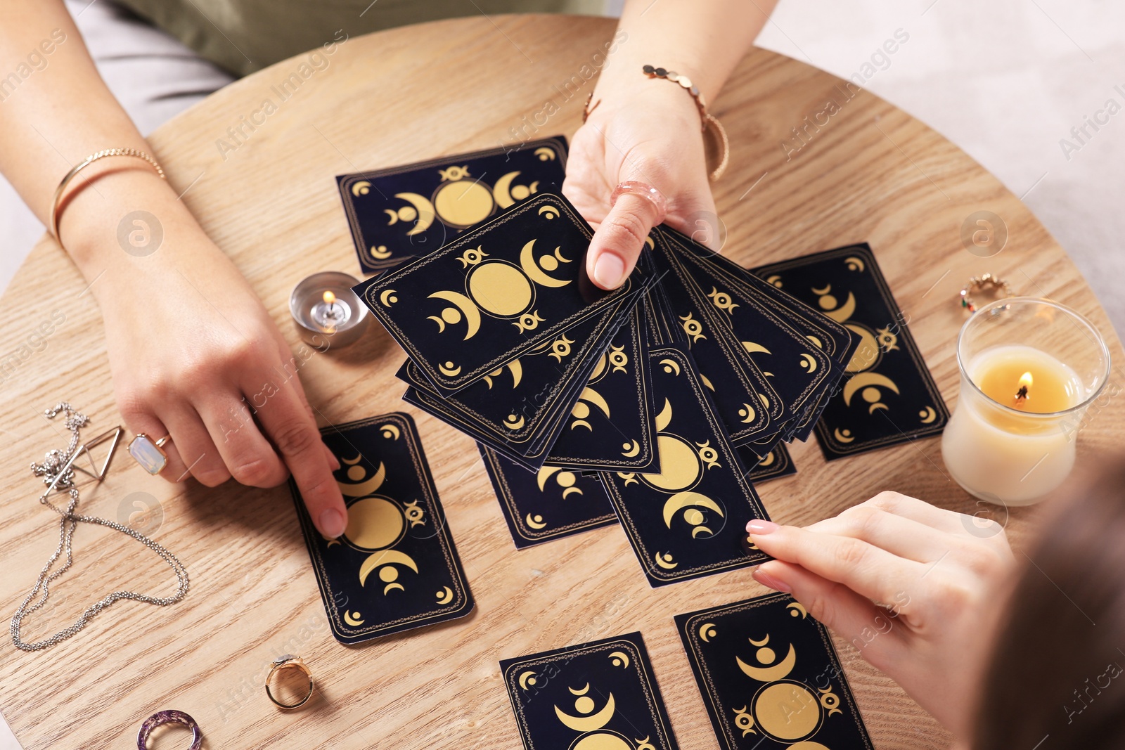 Photo of Woman pulling one tarot card at table indoors, closeup. Fortune telling