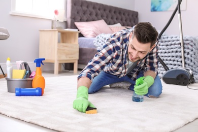 Photo of Mature man cleaning carpet at home