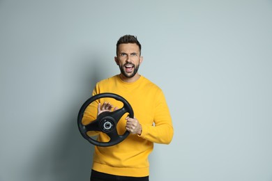 Photo of Emotional man with steering wheel on grey background