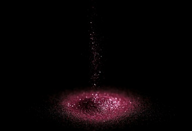 Photo of Sprinkling rose glitter on black background, bokeh effect