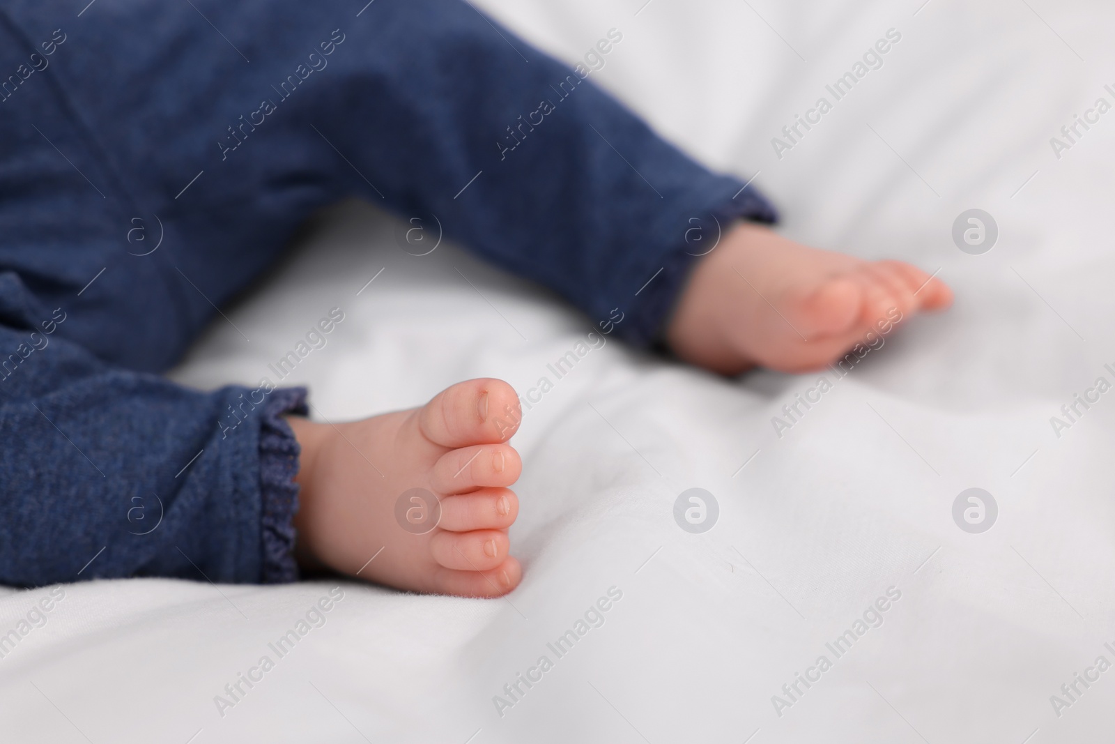 Photo of Newborn baby lying on white blanket, closeup